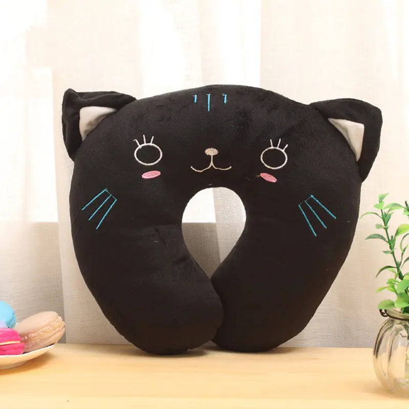 Black cat-shaped neck pillow on a wooden surface with a neutral background