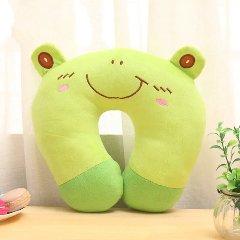 Green frog-shaped neck pillow on a table with a light background
