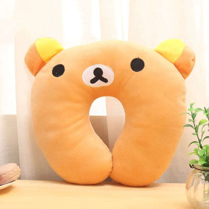 Orange bear-shaped neck pillow on a light surface with a blurred background